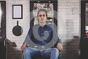 Portrait of handsome Asian man sitting at barbershop chair