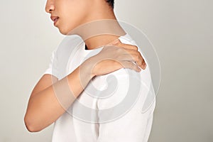 Portrait of handsome Asian man with uncomfortable face, suffering from neck pain. Medical and healthcare concept on white