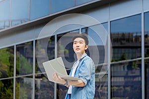 Portrait of handsome Asian student using computer laptop