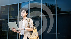 Portrait of handsome Asian student using computer laptop