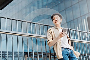Portrait of handsome Asian student using smartphone