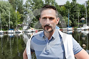 Portrait of handsome atractive businessman near of river with boats. River cruise for successful men