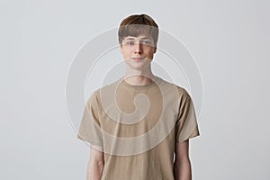 Portrait of handsome attractive young man with short haircut and blue eyes wears beige t shirt standing and smiling  over