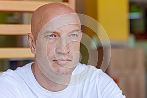 Portrait handsome bald man with blue eyes in a white t-shirt with a pensive