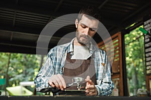 Portrait of handsome barista man making coffee while working in street cafe or coffeehouse outdoor