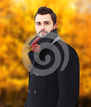 Portrait handsome bearded brunette man wearing a black coat in autumn day