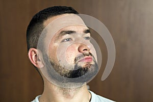 Portrait of handsome bearded confident intelligent modern photogenic young man with short haircut and black eyes looking