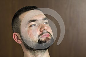 Portrait of handsome bearded confident intelligent modern photogenic young man with short haircut and black eyes looking