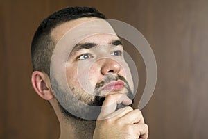 Portrait of handsome bearded confident intelligent modern photogenic young man with short haircut and black eyes looking