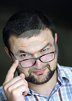 Portrait of handsome bearded intelligent modern photogenic young man in glasses with short haircut and kind black eyes smiling in