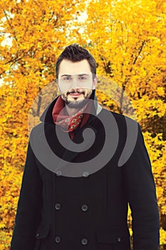 Portrait of handsome bearded man wearing black coat in autumn