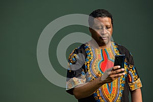 Portrait of handsome black man wearing traditional clothes and using mobile phone