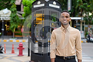 Portrait of handsome black young African businessman smiling outdoors in city