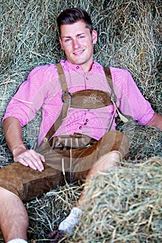 Handsome blond bavarian man sitting in hay