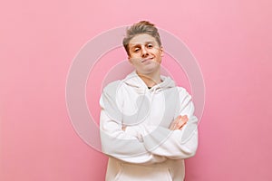 Portrait handsome blond boy in white casual clothes isolated on a pink background, looks into the camera and smiles.Young man in