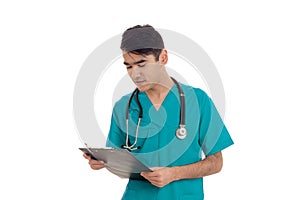 Portrait of handsome brunette male doctor in blue uniform with stethoscope posing and making notes isolated on white