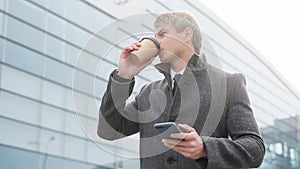 Portrait of handsome business man using smartphone and drinking