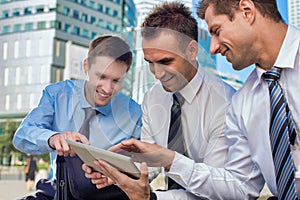 Portrait of handsome businessman showing business plan to the other businessman over digital tablet while sitting