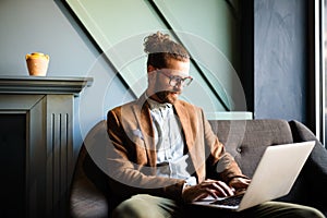 Portrait of handsome businessman smiling while using laptop in office