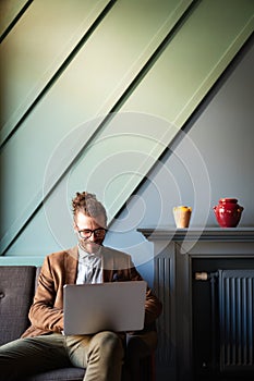 Portrait of handsome businessman smiling while using laptop in office