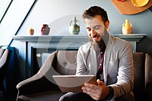 Portrait of handsome businessman smiling while using tablet in office