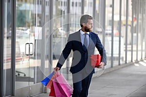 Portrait of an handsome businessman walking with shopping bag in a business center.