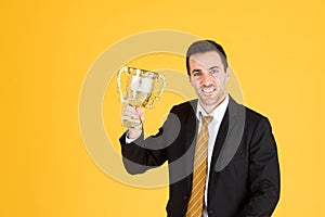 Portrait of a handsome businessman wearing white suit and tie while holding a golden trophy