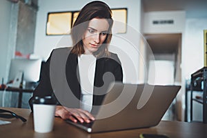 Portrait of handsome businesswoman using laptop computer at modern office.Blurred background.Horizontal.