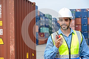 Portrait of handsome caucasian foreman or engineer man with white helmet and reflection shirt using walkie talkie for control