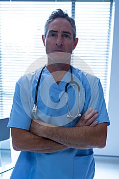 Male doctor standing with arms crossed in the hospital