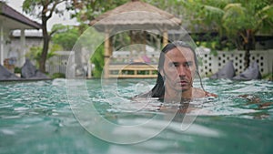 Portrait of handsome caucasian man, with Long Black Hair, Swimming in blue water