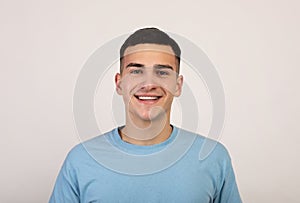 Portrait of handsome Caucasian young man in casual clothes smiling and looking at camera over light grey background