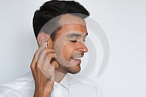 Portrait of handsome caucasian young man enjoying his favorite music. Happy smiling man in headphones against white wall