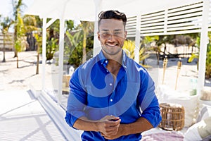 Portrait of handsome caucasian young man wearing blue shirt standing at tourist resort, copy space