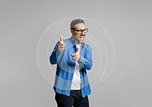 Portrait of handsome cheerful young businessman pointing at camera while posing on gray background