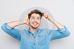 Portrait of handsome cheerful young man combing his hair