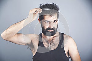 Portrait of handsome cheerful young man combing his hair