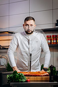 Portrait of handsome chef cooking raw meat in the kitchen. ÃÂ¡hef holds a professional kitchen knife. Concept of Cooking process