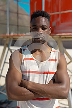 Portrait of handsome confident african american young man with arms crossed standing at beach