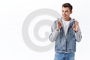 Portrait of handsome confident guy assuring in best quality of product, show okay signs and smiling, recommend promo
