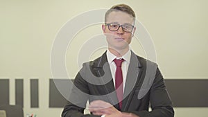 Portrait of a handsome confident young man in glasses and a beautiful suit looking in the camera crossing his arms in