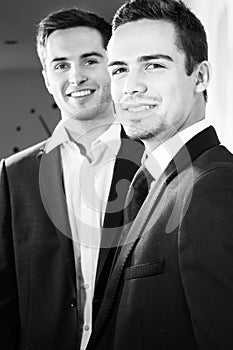 Portrait of handsome couple of men wearing suits smiling at camera