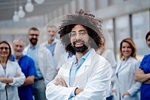 Portrait of handsome doctor standing in front of team of doctors. Healthcare team with doctors, nurses, professionals in