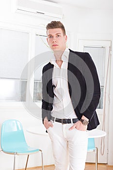 Portrait of a handsome fashionable man posing in the interior