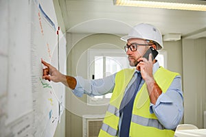 Portrait of handsome foreman construction worker man on industrial building industry construction site studying blueprint indoo