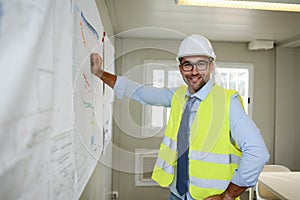 Portrait of handsome foreman construction worker man on industrial building industry construction site studying blueprint indoo