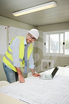 Portrait of handsome foreman construction worker man on industrial building industry construction site studying blueprint indoo