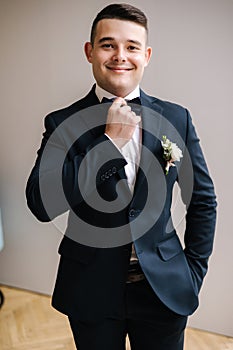Portrait of handsome groom in dark blue suit preparing for first view with bride. Wedding day