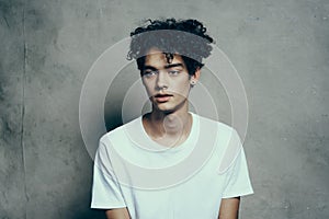 portrait of a handsome guy with curly hair on a gray background white t-shirt close-up model