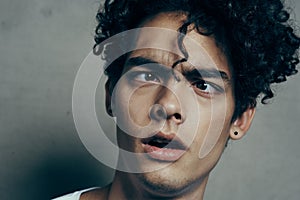 portrait of a handsome guy with curly hair on a gray background white t-shirt close-up model